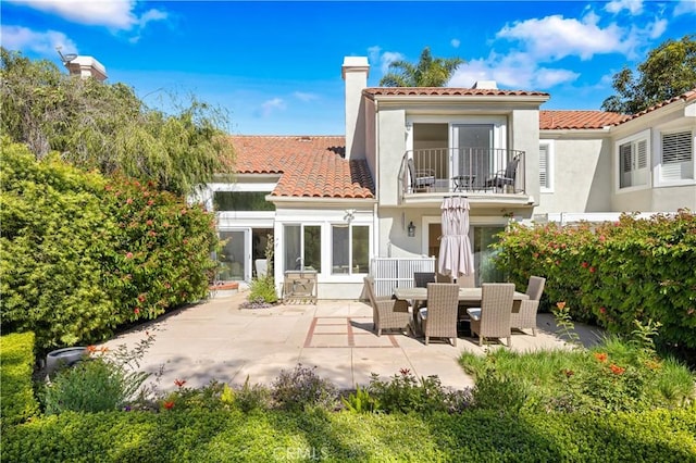 back of house featuring a patio area, a chimney, a tile roof, and a balcony