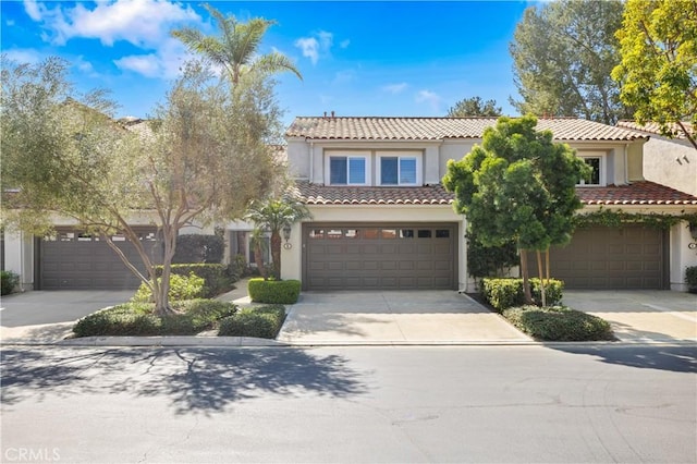 mediterranean / spanish-style house featuring a garage, a tile roof, driveway, and stucco siding