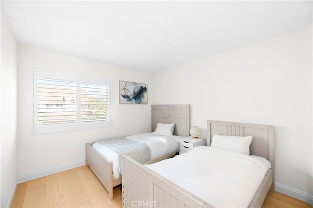 bedroom featuring baseboards and light wood finished floors