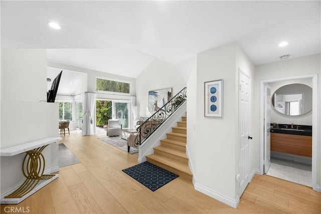 entryway featuring recessed lighting, light wood-style floors, vaulted ceiling, baseboards, and stairs