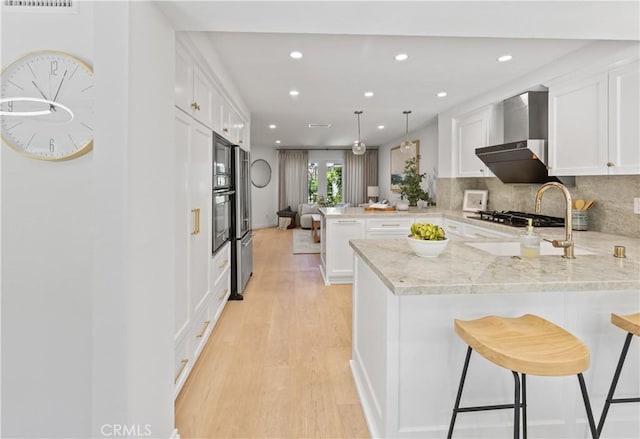 6 Baristo Unit 39, Irvine, CA 92612 - kitchen featuring a peninsula, wall chimney range hood, white cabinetry, light wood finished floors, and recessed lighting