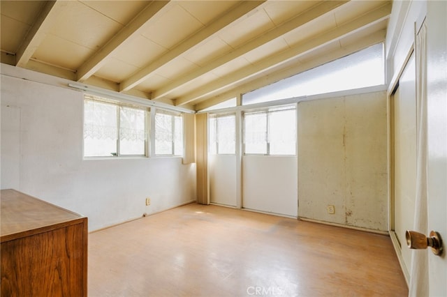 empty room featuring lofted ceiling with beams