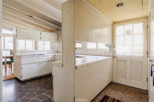 kitchen with tile countertops, white cabinetry, and ornamental molding