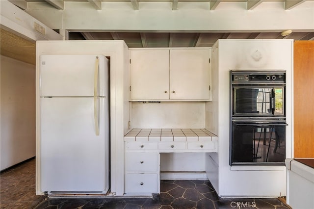 kitchen featuring tile countertops, white cabinetry, freestanding refrigerator, and dobule oven black