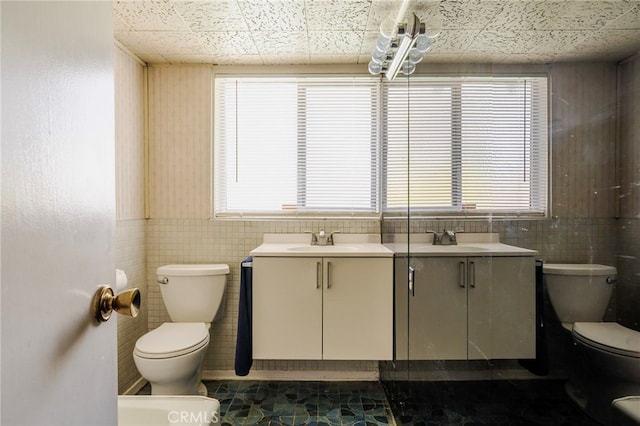 bathroom featuring wainscoting, vanity, toilet, and tile walls