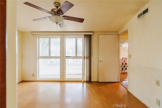 empty room with a ceiling fan, light wood-type flooring, and visible vents