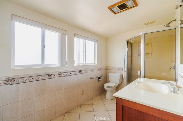 bathroom featuring toilet, a wainscoted wall, tile patterned floors, vanity, and a shower stall