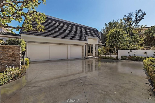 view of home's exterior featuring a tile roof, stucco siding, fence, a garage, and driveway