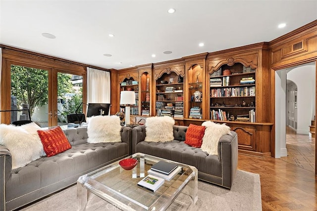 living room featuring arched walkways, french doors, ornamental molding, and recessed lighting