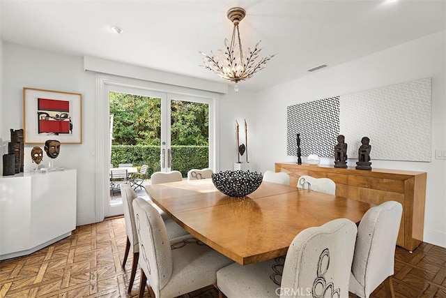 dining space featuring baseboards, visible vents, and a notable chandelier
