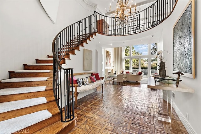 staircase with baseboards, a high ceiling, and a chandelier