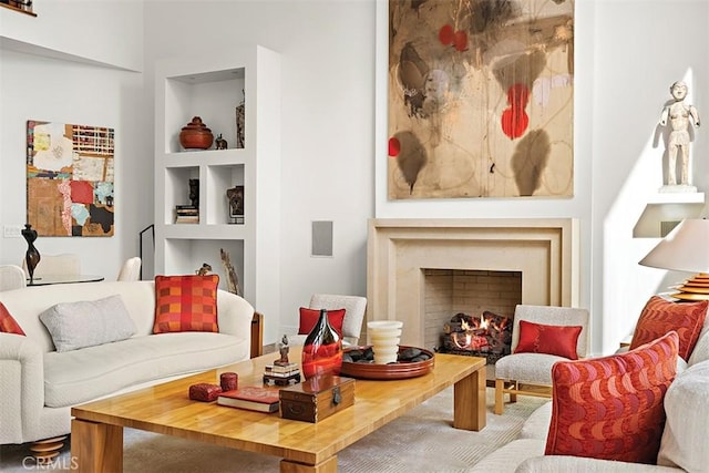 living area featuring built in shelves and a lit fireplace