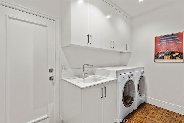 washroom featuring cabinet space, baseboards, washer and clothes dryer, and a sink