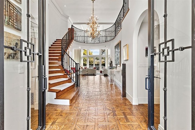 entrance foyer featuring arched walkways, a chandelier, a high ceiling, baseboards, and stairway