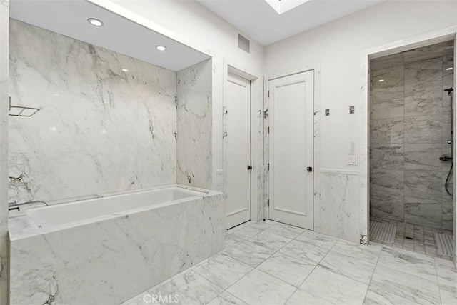 bathroom with a skylight, marble finish floor, a garden tub, a marble finish shower, and recessed lighting