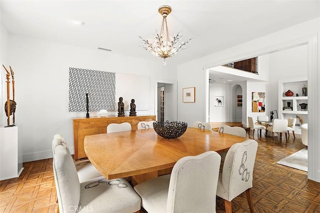 dining room with arched walkways, visible vents, baseboards, and an inviting chandelier