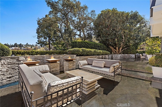 view of patio with an outdoor living space with a fire pit
