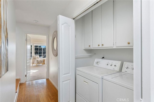 laundry area with cabinet space, baseboards, washer and clothes dryer, and light wood finished floors