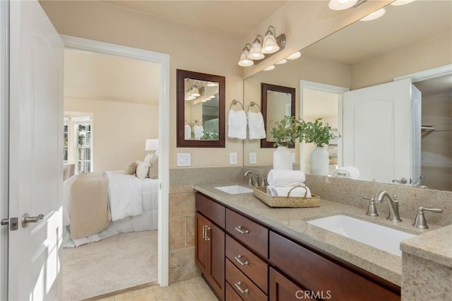 ensuite bathroom with double vanity, ensuite bath, tile walls, and a sink