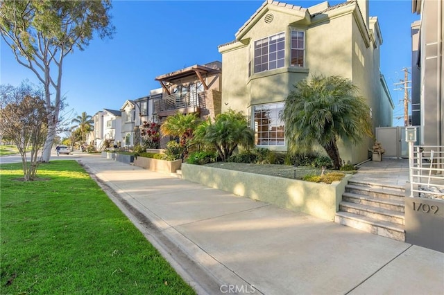 exterior space with a residential view, a tiled roof, a front lawn, and stucco siding