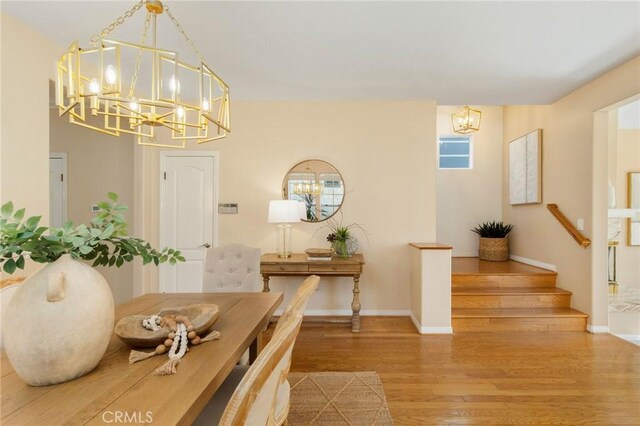 dining area featuring a chandelier, stairs, baseboards, and wood finished floors