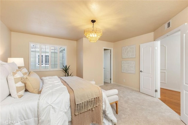 carpeted bedroom featuring visible vents, baseboards, and an inviting chandelier