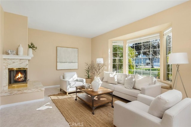 carpeted living room featuring a premium fireplace and baseboards