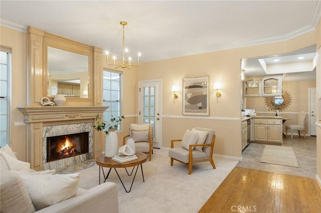 sitting room featuring a high end fireplace, a notable chandelier, crown molding, and baseboards