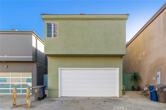 view of front facade with concrete driveway, an attached garage, and stucco siding