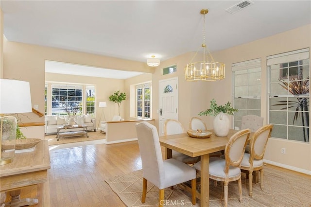 dining area featuring a chandelier, baseboards, visible vents, and hardwood / wood-style floors