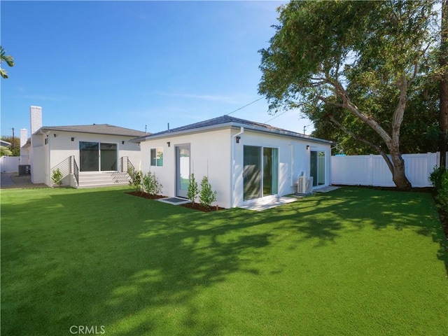 back of property featuring a yard, fence, and stucco siding