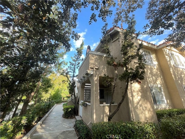 view of home's exterior with a tile roof and stucco siding