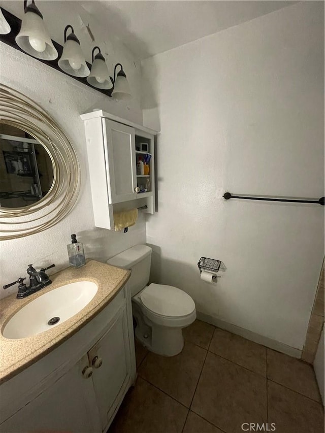 bathroom featuring vanity, tile patterned flooring, toilet, and baseboards