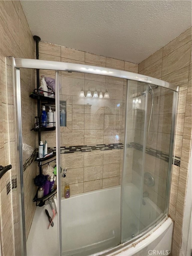 full bath with a textured ceiling and bath / shower combo with glass door