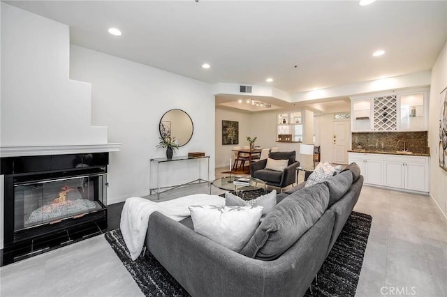 living area with visible vents, baseboards, recessed lighting, indoor wet bar, and a tiled fireplace