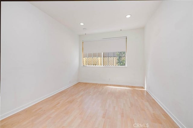 unfurnished room with light wood-style flooring, recessed lighting, and baseboards