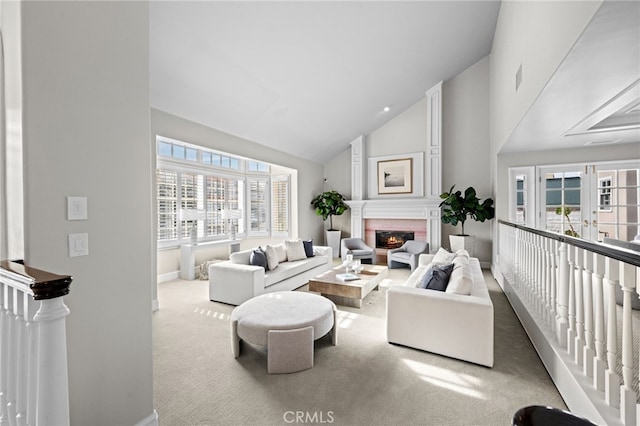 carpeted living room with a glass covered fireplace, baseboards, visible vents, and high vaulted ceiling