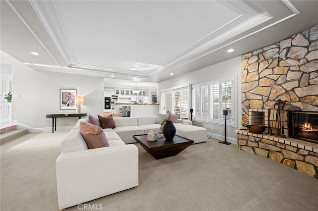 carpeted living area featuring a tray ceiling, a fireplace, and ornamental molding