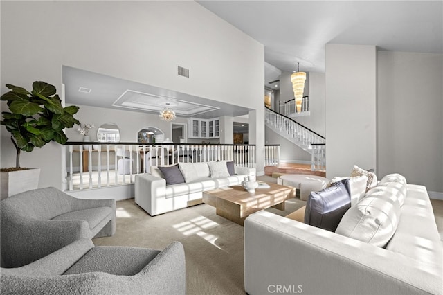 carpeted living room with a notable chandelier, visible vents, stairs, and a towering ceiling