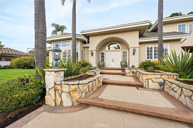 doorway to property with a chimney and stucco siding