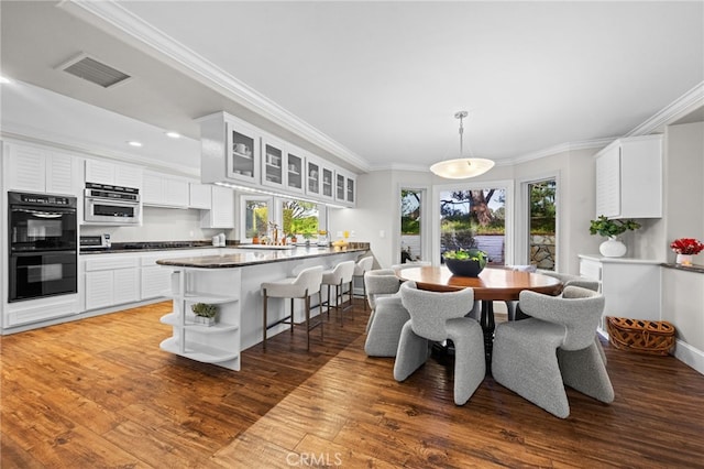 dining room with recessed lighting, visible vents, wood finished floors, and ornamental molding