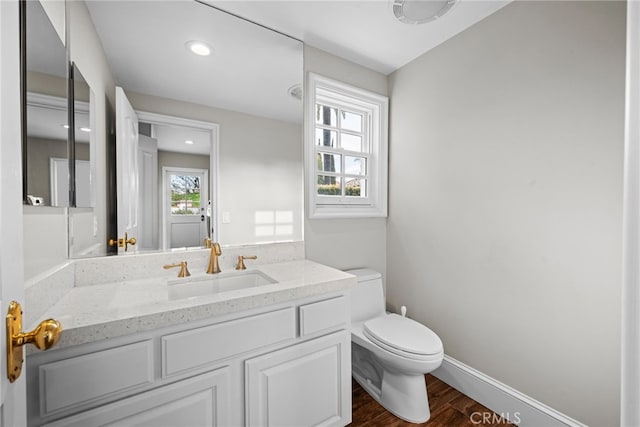 bathroom featuring toilet, wood finished floors, recessed lighting, baseboards, and vanity