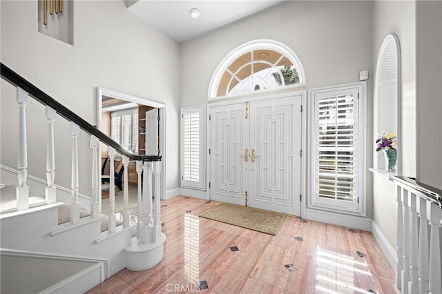 entrance foyer featuring stairway, a high ceiling, and baseboards