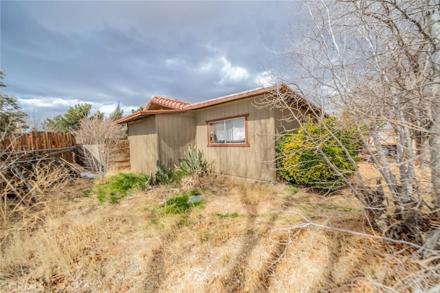 view of side of property featuring a tile roof and fence