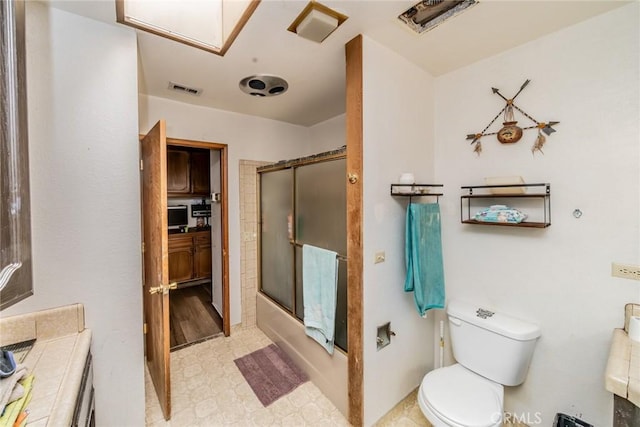 full bath featuring toilet, visible vents, vanity, combined bath / shower with glass door, and tile patterned floors