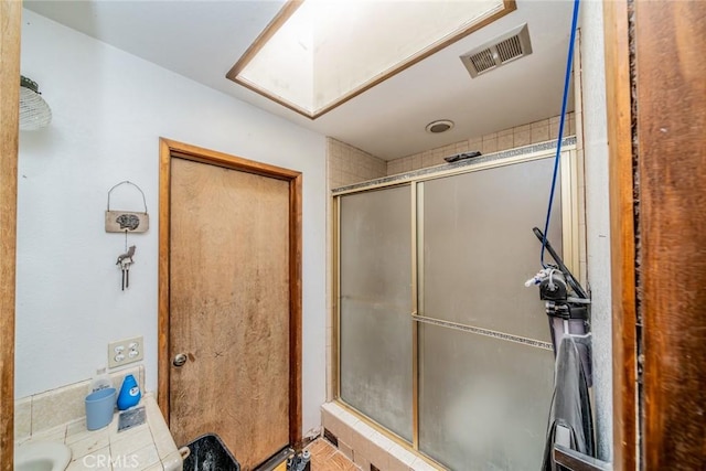 full bath with a skylight, visible vents, and a shower stall