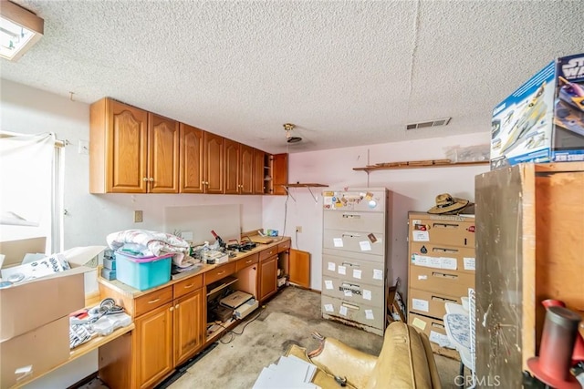 kitchen with refrigerator, brown cabinets, visible vents, a textured ceiling, and unfinished concrete floors