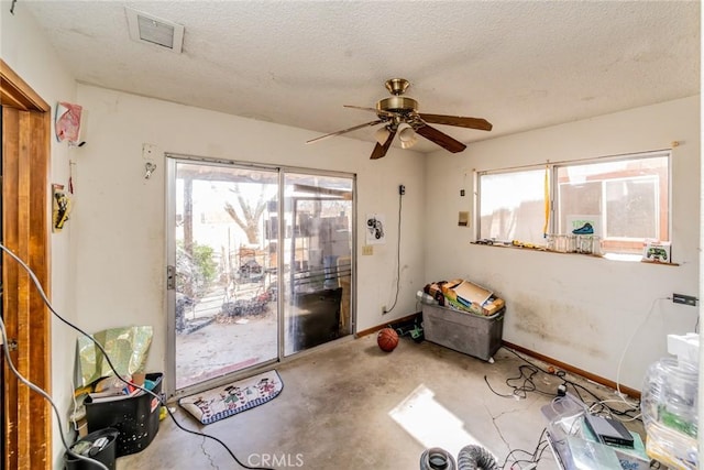 interior space featuring baseboards, visible vents, ceiling fan, a textured ceiling, and concrete floors