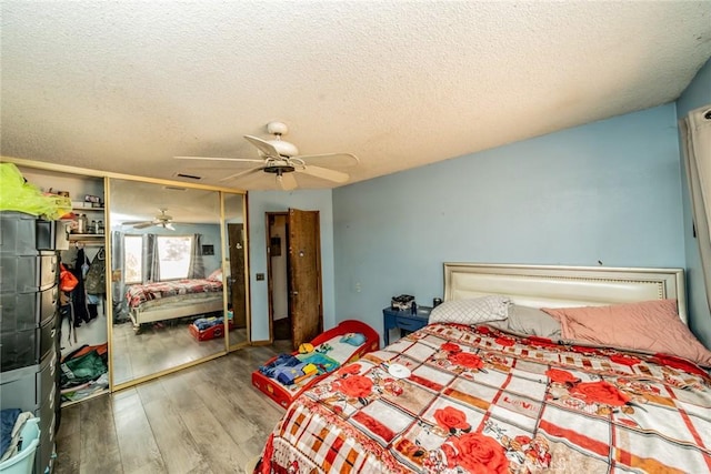 bedroom featuring a textured ceiling, ceiling fan, a closet, and wood finished floors