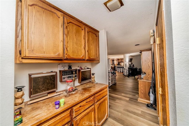 kitchen with light wood-style floors, light countertops, brown cabinets, and a textured ceiling